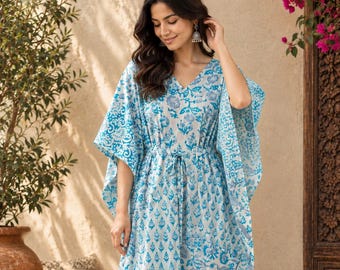 May include: A floor-length kaftan dress featuring a white base with a blue floral and geometric block print pattern, a V-neckline, wide kimono-style sleeves, and a drawstring waist tie that cinches the fabric at the center.