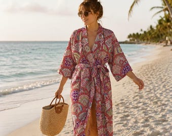 May include: A long, wrap-style robe featuring a vibrant, multi-colored fan-shaped pattern in shades of red, purple, and green, with wide sleeves and a matching tie belt, paired with a woven straw tote bag with brown leather handles.
