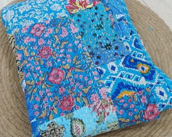 May include: A folded quilt featuring a vibrant patchwork design with various shades of blue, pink, and white floral and geometric patterns. The fabric is stitched with visible white running thread throughout, creating a textured kantha style finish.
