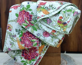 May include: A white cotton quilt featuring a vibrant floral and bird pattern with shades of red, pink, orange, and green. The fabric displays intricate kantha stitching throughout, creating a textured surface with visible running stitches in a light color.