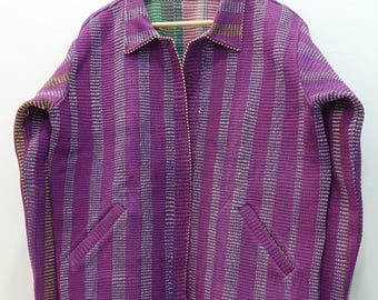 May include: A long-sleeve jacket featuring a vibrant purple base with vertical stripes in shades of pink, white, and yellow. The jacket includes a standard collar, a front button closure, and two side pockets, all constructed from a textured fabric.