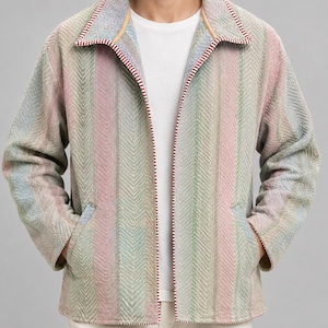 May include: A long-sleeve jacket featuring a multi-colored herringbone pattern in shades of soft pink, light green, and blue. The jacket has a wide collar with a red and white striped trim along the edges, two front pockets, and a plain white t-shirt.