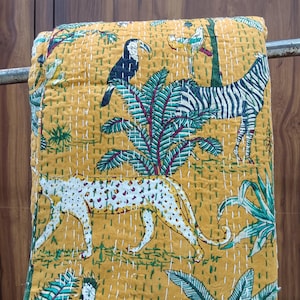 May include: A mustard yellow cotton quilt featuring a repeating jungle-themed print with a black and white zebra, a spotted leopard, a toucan, and various tropical birds amidst green palm leaves and foliage, finished with white hand-stitched kantha detailing.