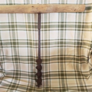 May include: A vintage hand drill with a wooden handle and a metal drill bit. The drill bit is a spiral auger bit.