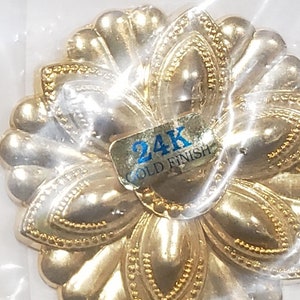 Könnte beinhalten: Ein goldfarbenes, blütenförmiges Dekorationsstück aus Metall mit einem blauen Etikett mit der Aufschrift "24K Gold Finish".
