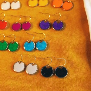 May include: Assortment of colorful round earrings with gold hooks. The earrings are in shades of blue, green, red, purple, white, and black.