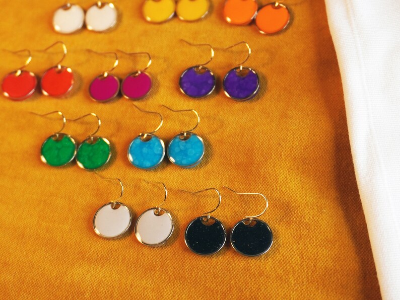 May include: Assortment of colorful round earrings with gold hooks. The earrings are in shades of blue, green, red, purple, white, and black.