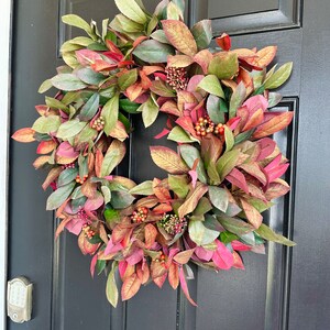 Pode incluir: Uma coroa de outono com folhas e bagas verdes e vermelhas. A coroa &eacute; feita de folhagem artificial e &eacute; perfeita para decorar uma porta de entrada.