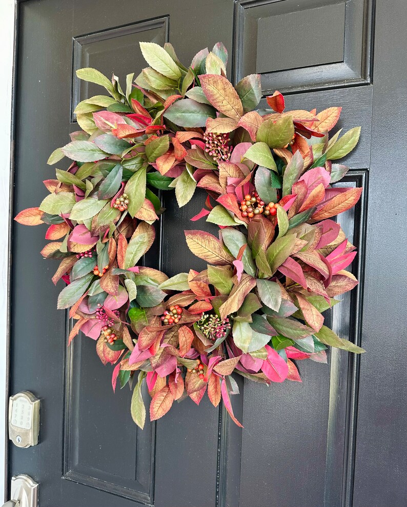 Pode incluir: Uma coroa de outono com folhas e bagas verdes e vermelhas. A coroa &eacute; feita de folhagem artificial e &eacute; perfeita para decorar uma porta de entrada.