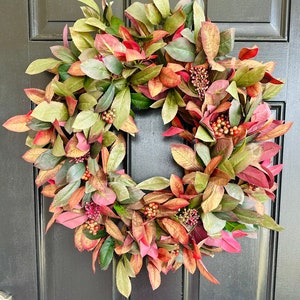 Pode incluir: Uma coroa de outono com folhas e bagas verdes e vermelhas. A coroa &eacute; feita de folhagem artificial e &eacute; perfeita para decorar uma porta de entrada.