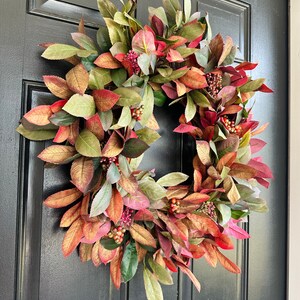 Pode incluir: Uma coroa de outono com folhas de cor bord&ocirc;, verde e dourado e bagas vermelhas. A coroa &eacute; feita de folhagem artificial e &eacute; perfeita para decorar uma porta de entrada.