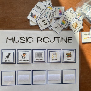 Pode incluir: Um quadro branco com as palavras "MUSIC ROUTINE" escritas em marcador preto. O quadro é dividido em oito seções, cada uma com uma borda azul e uma tira de velcro branca. As seções são rotuladas como "Stretch", "Vocal Exercises", "Repertoire", "Diction", "Rhythm", e três seções em branco. Há vários cartões coloridos com imagens e texto espalhados ao redor do quadro.