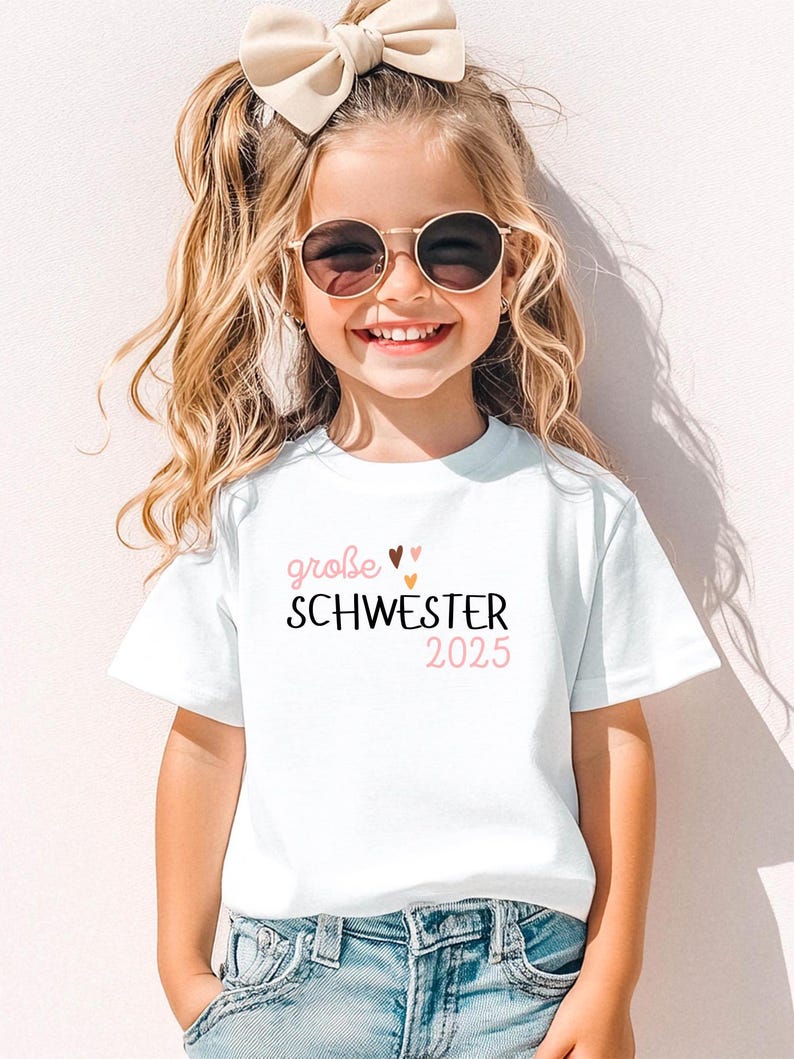 personalisiertes weißes t-shirt mit dem text große schwester 2025, mit boho herz Motiv. t-shirt zur schwangerschaft verkünden.