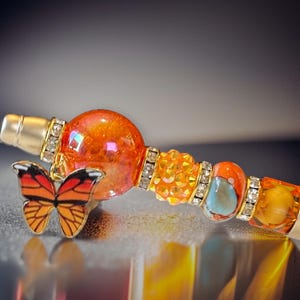 Pluma con cuentas de mariposa monarca