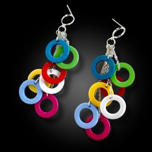 May include: A pair of colorful dangle earrings. Each earring features a silver-tone ear wire and chain, with multiple brightly colored, circular charms in shades of blue, green, red, yellow, white, and pink. The earrings are set against a black background.
