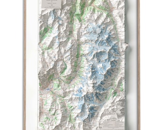 以下が含まれることがあります： アルプスの山脈、モンブラン周遊の3D地図が額装されています。地図は紙に印刷されており、山の標高を示すために立体的な質感があります。地図は明るい木製の額縁に入っています。