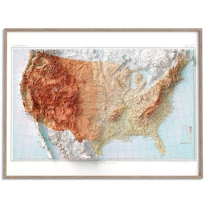 Könnte beinhalten: Eine gerahmte 3D-Reliefkarte der Vereinigten Staaten, die die Topographie des Landes zeigt. Die Karte verwendet einen Farbverlauf von Braun bis Beige, mit einem hellblauen Hintergrund. Sie ist in einem hellbraunen Holzrahmen eingefasst.
