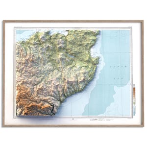 May include: A framed topographic map of Scotland featuring a three-dimensional relief effect. The map displays mountainous terrain in shades of green and brown, contrasting with the light blue North Sea. It includes grid lines and text labels.