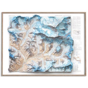 Peut inclure: Une carte topographique 3D encadrée du Mont Everest, avec un relief détaillé des pics et des vallées. La carte utilise des nuances de bleu, de marron et de blanc, avec des étiquettes textuelles. Le cadre est en bois brun clair.