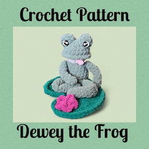 Op de afbeelding: Een gehaakt kikkerpatroon toont Dewey, een grijze kikker met een roze sjaal en grote ogen, zittend op een groen waterlelieblad met een roze bloem. De woorden "Crochet Pattern" en "Dewey the Frog" zijn te zien.
