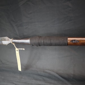 May include: A wooden-handled spear with a black leather wrap and a metal tip. The spear is about 48 inches long.