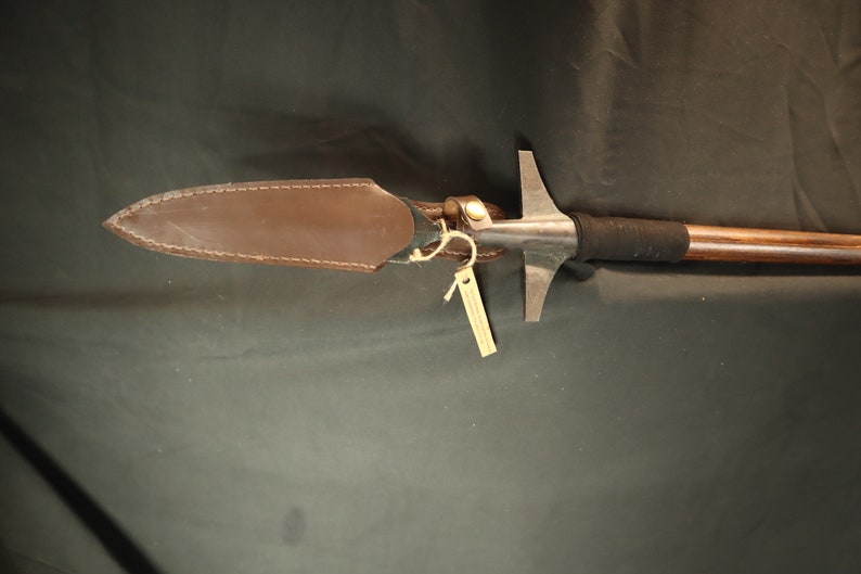 Peut inclure: Une lance avec un manche en bois et une pointe de lance en m&eacute;tal. La pointe de lance est recouverte d'un &eacute;tui protecteur en cuir marron. Une petite &eacute;tiquette est suspendue &agrave; la lance.