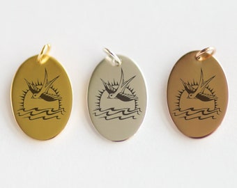 May include: Three oval-shaped pendants with a black and white image of a bird flying over a sun and waves. The pendants are in gold, silver, and rose gold.