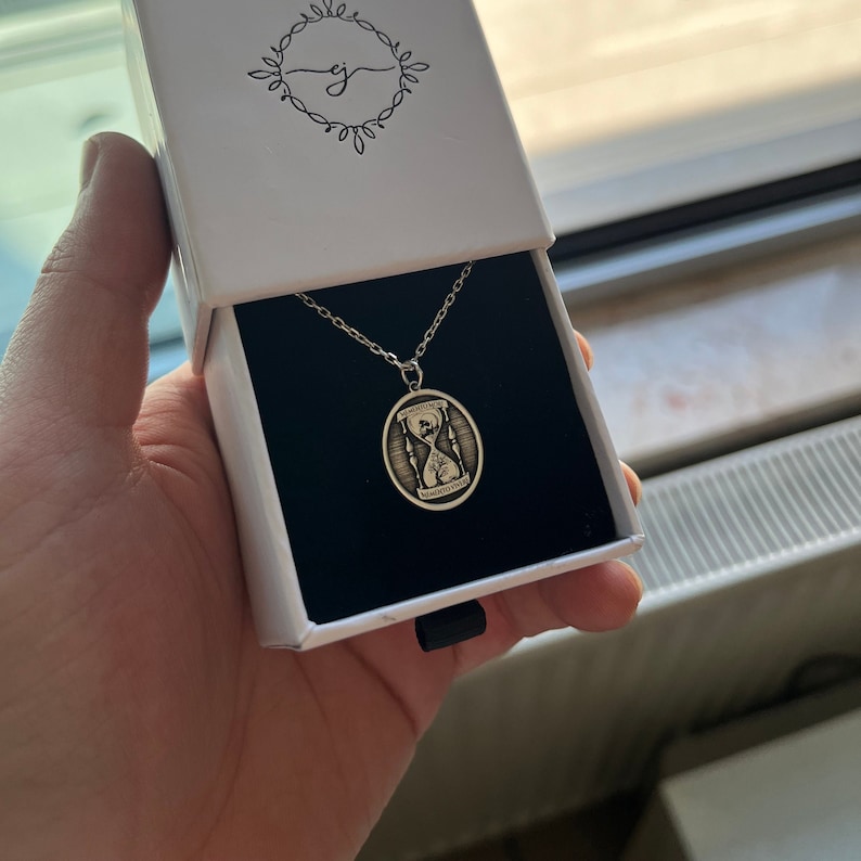 Pu&ograve; includere: Una collana d'argento con un ciondolo a forma di clessidra. Il ciondolo &egrave; inciso con le parole "Momenti come questi" e "Momenti da custodire".
