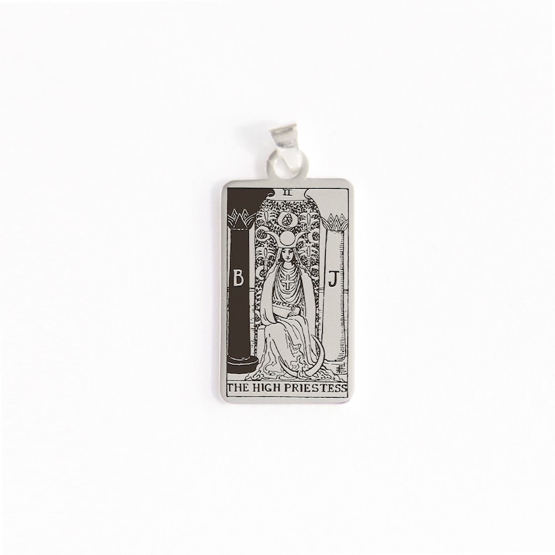Op de afbeelding: Zilveren hanger met een zwart-witte illustratie van de tarotkaart Hogepriesteres. De kaart toont een vrouw die op een troon zit met een halve maan boven haar hoofd. De kaart wordt omlijst door twee pilaren met de letters B en J erop. De tekst "THE HIGH PRIESTESS" staat onderaan de kaart gedrukt.