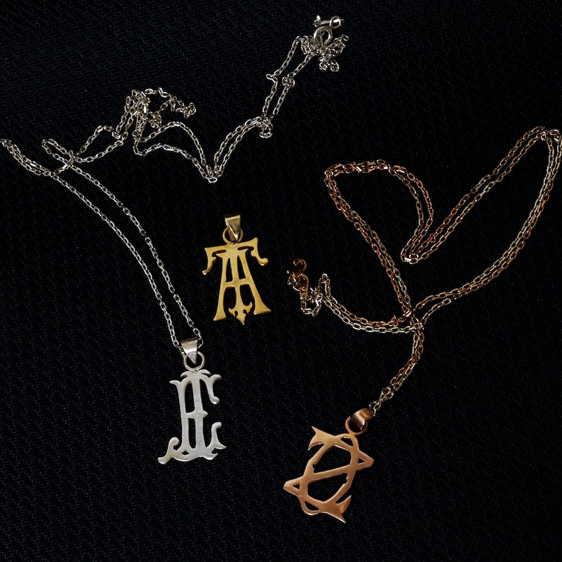 May include: Three silver necklaces with different pendants. The pendants are in the shape of letters. The first pendant is a gold letter "A", the second pendant is a silver letter "H", and the third pendant is a silver letter "Z".