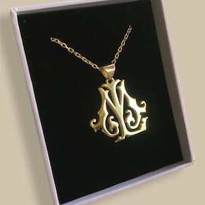 May include: A gold-colored necklace with a pendant featuring a stylized letter 'N' and 'Y' design. The necklace is displayed in a white box with a black velvet interior.