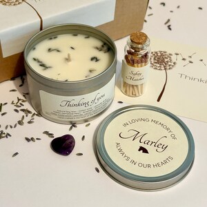 May include: A soy wax candle in a silver tin with a label reading Thinking of you, a small glass bottle of safety matches, a heart-shaped amethyst stone, and a candle lid with the text In Loving Memory of Marley Always in our hearts.
