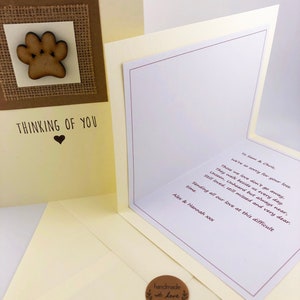 Op de afbeelding: Een condoleancekaart met een houten pootprint op een jute achtergrond. De kaart heeft de tekst "Thinking of You" met een hart. De binnenkant van de kaart heeft een handgeschreven condoleancebericht.