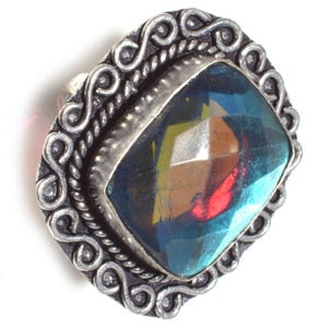 May include: A silver ring with a large, faceted, iridescent blue gemstone set in a decorative, ornate silver setting.