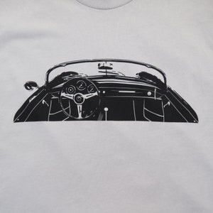 May include: Black and white silhouette of a classic car's interior, showing the steering wheel and dashboard.