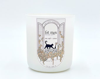 May include: White soy wax candle with a black cat illustration on the label. The label says "fat max design co" and "sea salt + citrus". The candle is 13 oz.