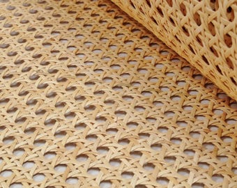 Könnte beinhalten: Nahaufnahme eines gewebten Rohrgeflechts, das oft für Stuhlsitze und -lehnen verwendet wird. Das Material ist hellbraun und hat ein Rautenmuster.