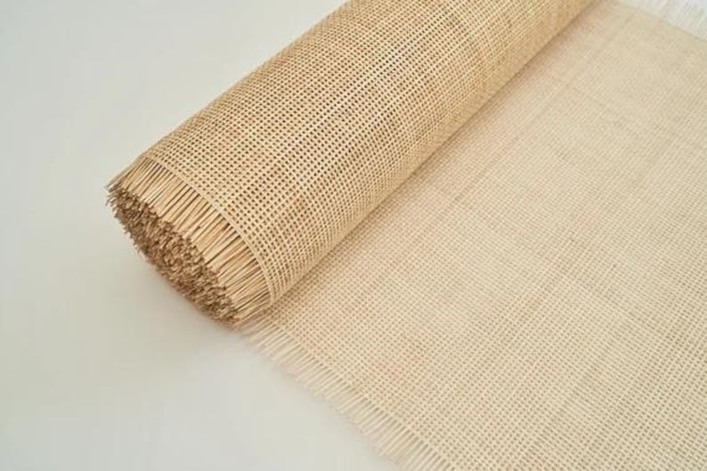 K&ouml;nnte beinhalten: Eine Rolle aus nat&uuml;rlichem Rohrgeflecht, ein gewebtes Material, das f&uuml;r Stuhlsitze und andere M&ouml;belprojekte verwendet wird. Das Geflecht ist beigefarben und hat einen Fransenrand.