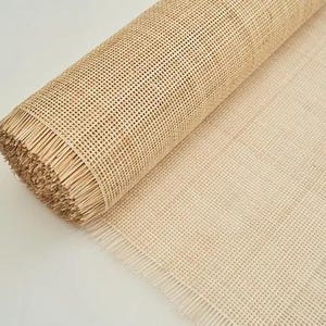 May include: A roll of natural cane webbing, a woven material used for chair seats and other furniture projects. The webbing is beige in colour and has a fringed edge.
