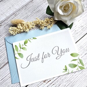 May include: A white card with a light blue envelope. The card has a watercolor design of green leaves and the text "Just for You" in gray script.