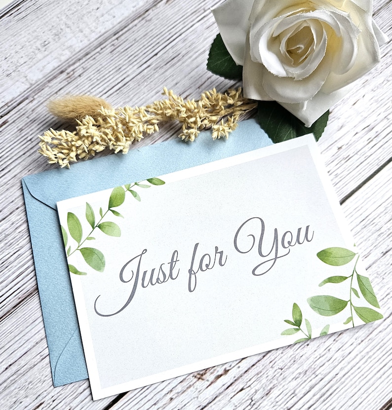 May include: A white card with a light blue envelope. The card has a watercolor design of green leaves and the text "Just for You" in gray script.