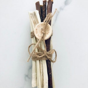 May include: A bundle of natural sticks and twigs tied together with twine and a wooden button with the text "Handmade with love" on it.