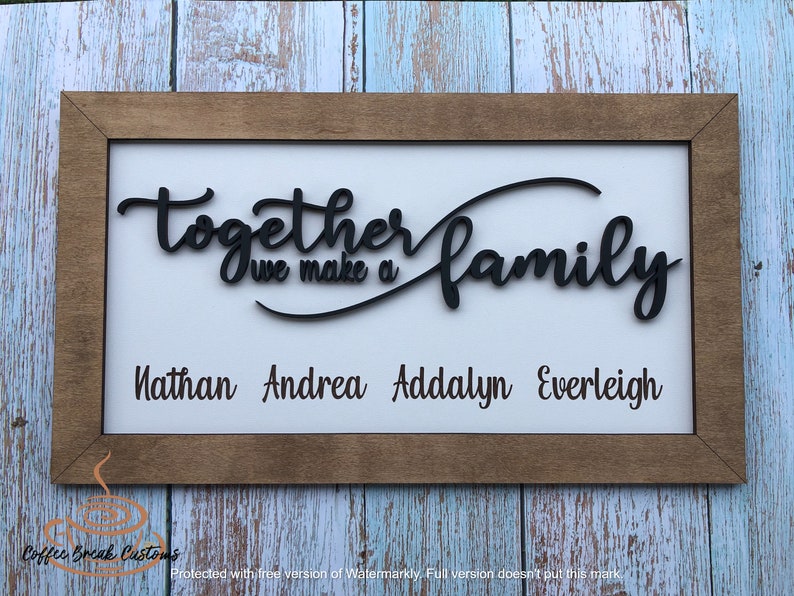 Op de afbeelding: Een houten ingelijst bord met de tekst "Together we make a family" in zwarte cursieve letters. De namen Nathan, Andrea, Addalyn en Everleigh staan eronder in zwarte letters.