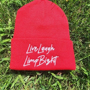 May include: Red knit beanie with white embroidered text that reads "Live Laugh Limp Bizkit".