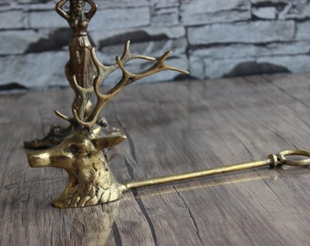 May include: A gold-toned metal deer head fireplace tool with a long handle. The deer head has a detailed design with antlers and a realistic face.
