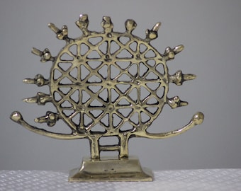 May include: A gold metal decorative stand with a round top and three legs. The top features a circular design with a geometric pattern.