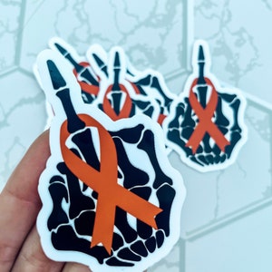 May include: A set of four stickers featuring a black skeleton hand giving the middle finger with an orange ribbon tied around the index finger.