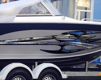 Könnte beinhalten: Ein weißes und marineblaues Motorboot auf einem Anhänger, mit dem Text "UMS-600" in Weiß. Das Boot hat ein silbernes und blaues Grafikdesign an der Seite. Es ist mit einem orangefarbenen Gurt gesichert.
