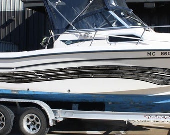 May include: A white Grady-White boat with black accents and a blue hull is on a trailer. The boat has a black canvas top and a windshield. The boat's registration number is MC 8600 TK.