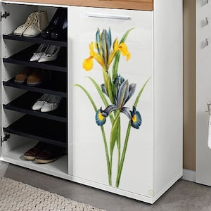 May include: White shoe cabinet with a wood top and a floral design on the front. The design features yellow and blue irises on a white background.